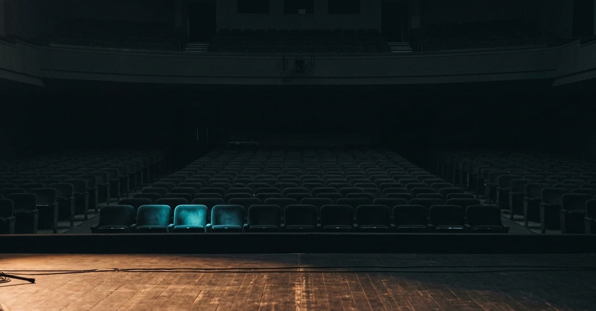 The view from an empty stage: a spotlight glow and rows of seats receding into darkness