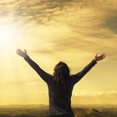 woman reaching for the sky and sun